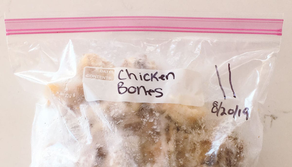 A sealed, labeled, and dated plastic bag filled with a frozen chicken carcass.